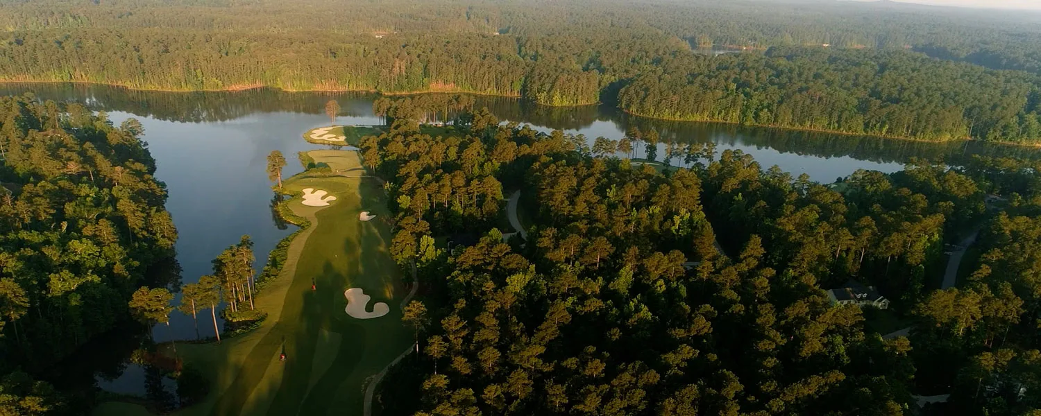 Aerial photograph of a Monticello fairway running toward a lake cove between dense pine forest
