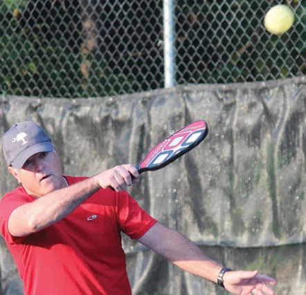 Actual photograph of a village pickleball player hitting a forehand