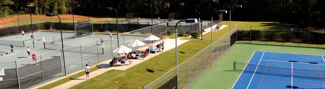 Actual panoramic photograph of the clay tennis courts, shaded seating and hard courts at the recreation complex