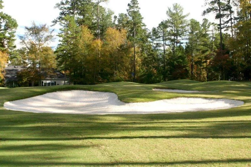 Photograph of a large white bunker guarding a Tara green with autumn trees behind